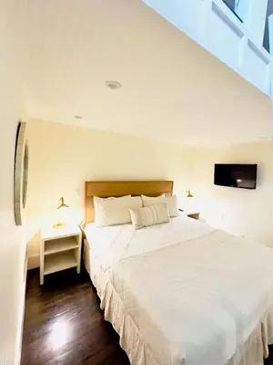 a bedroom with a large white bed and a tv at Zen Den Cottage in Rosemary Beach