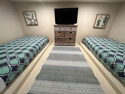 two beds in a room with a tv on the wall at Zen Den Cottage in Rosemary Beach