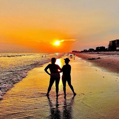 two people standing on the beach watching the sunset at Zen Den Cottage in Rosemary Beach