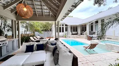 a living room with a white couch and a swimming pool at Zen Den Cottage in Rosemary Beach