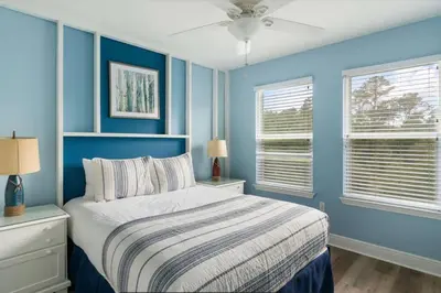 a blue bedroom with a bed and two windows at Beautiful 4 bedroom near Rosemary Beach! in Inlet Beach