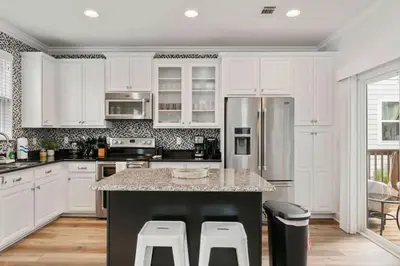 a kitchen with white cabinets and a island with bar stools at Beautiful 4 bedroom near Rosemary Beach! in Inlet Beach