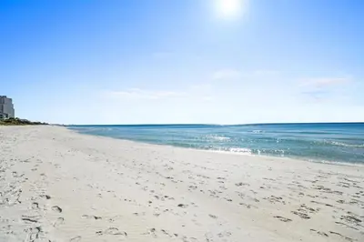 a beach with footprints in the sand and the ocean at 30A Emerald Hill Beach Resort by Panhandle Getaways in Santa Rosa Beach
