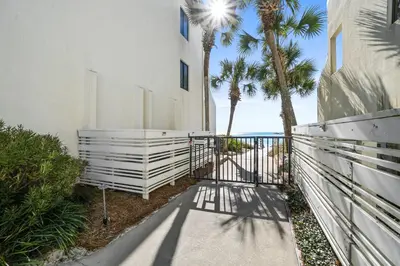a walkway leading to a white building with palm trees at 30A Emerald Hill Beach Resort by Panhandle Getaways in Santa Rosa Beach