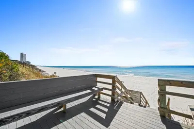 a wooden bench sitting on a boardwalk next to the beach at 30A Emerald Hill Beach Resort by Panhandle Getaways in Santa Rosa Beach