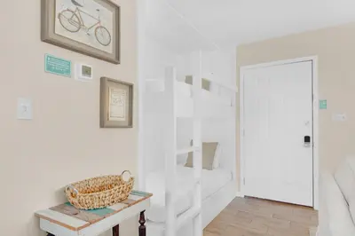 a white room with a staircase and a basket on a table at Beachwood Villas 1A- Beach Haven in Santa Rosa Beach