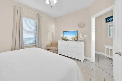 a white bedroom with a bed and a tv at Celadon 1103 - Beach Paradise in Panama City Beach