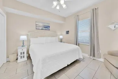 a white bedroom with a bed and a couch at Celadon 1103 - Beach Paradise in Panama City Beach
