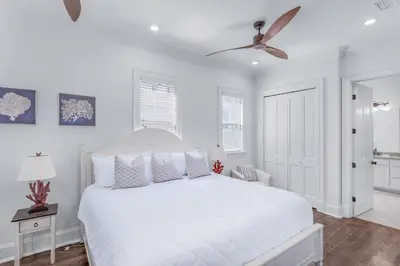 a white bedroom with a white bed and a ceiling fan at Seas the Day on 30A in Santa Rosa Beach