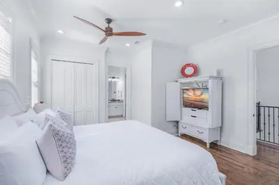 a white bedroom with a bed and a tv at Seas the Day on 30A in Santa Rosa Beach