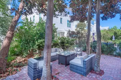 a patio with a table and chairs between trees at Seas the Day on 30A in Santa Rosa Beach