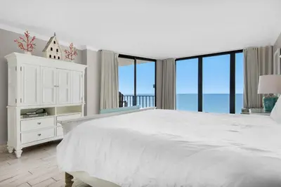 a white bedroom with a large bed and large windows at Edgewater Tower 3-1012 in Panama City Beach