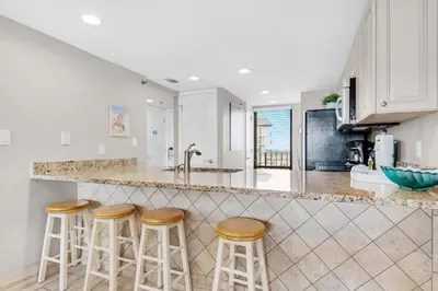 a kitchen with three bar stools at a counter at Edgewater Tower 3-1012 in Panama City Beach