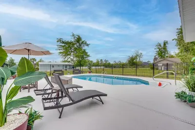 a swimming pool with lounge chairs and an umbrella at Southport Getaway with Private Pool about 15 Mi to PCB! in Southport