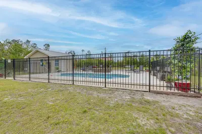 a metal fence with a pool in a yard at Southport Getaway with Private Pool about 15 Mi to PCB! in Southport
