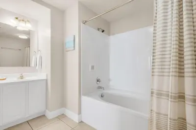 a white bathroom with a tub and a sink at Sunrise Beach #903 in Panama City Beach
