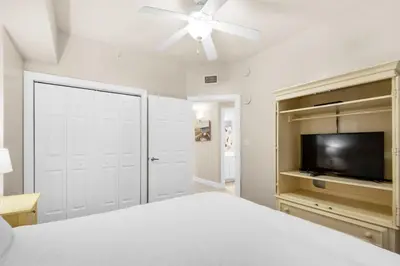 a bedroom with a white bed and a flat screen tv at Sunrise Beach #903 in Panama City Beach