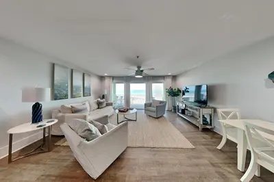 a living room with white furniture and a tv at Commodores Retreat #205 in Santa Rosa Beach