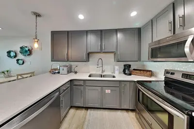 a kitchen with stainless steel appliances and gray cabinets at Commodores Retreat #205 in Santa Rosa Beach
