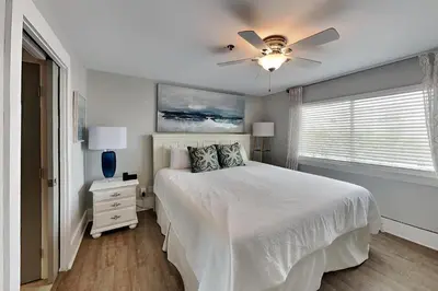 a white bedroom with a bed and a ceiling fan at Commodores Retreat #205 in Santa Rosa Beach