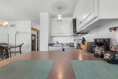 a kitchen with white cabinets and a wooden counter top at Top of the Gulf 807 in Panama City Beach