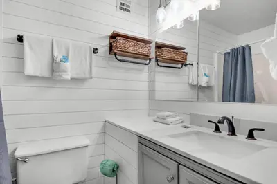 a bathroom with a sink and a toilet and a mirror at Top of the Gulf 807 in Panama City Beach
