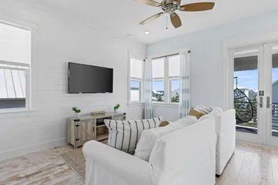 a living room with white furniture and a flat screen tv at Flor Da Li by the Sea in Inlet Beach