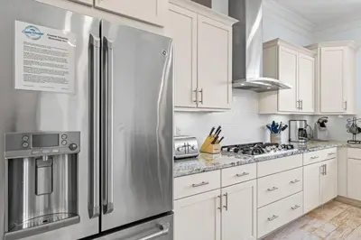 a kitchen with white cabinets and a stainless steel refrigerator at Flor Da Li by the Sea in Inlet Beach