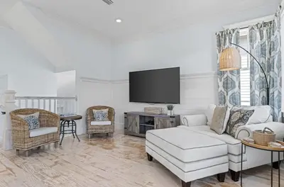 a living room with a white couch and a tv at Flor Da Li by the Sea in Inlet Beach