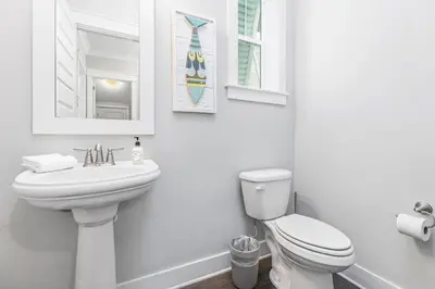 a white bathroom with a toilet and a sink at Prominence 30A - Lucky Old Sun in Panama City Beach