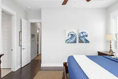 a bedroom with a blue and white bed and a hallway at Prominence 30A - Lucky Old Sun in Panama City Beach