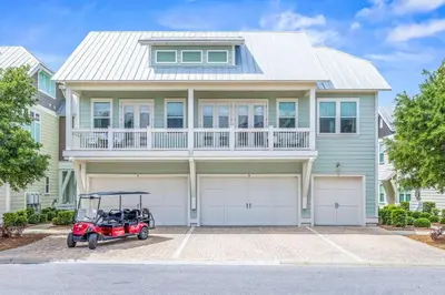 a house with a golf cart parked in front of it at Prominence 30A - Lucky Old Sun in Panama City Beach