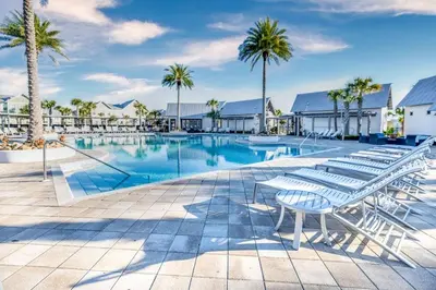 a swimming pool with lounge chairs and palm trees at Prominence 30A - Lucky Old Sun in Panama City Beach