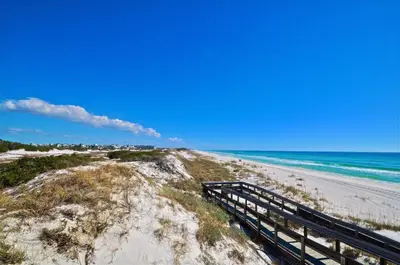 a beach with a wooden boardwalk leading to the ocean at Prominece 30A - Beach Retreat in Santa Rosa Beach