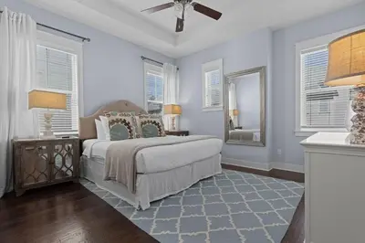 a bedroom with a bed with a ceiling fan and windows at Prominence 30A - Coastal Cottage in Panama City Beach