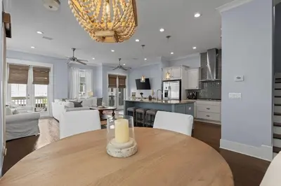 a dining room and living room with a candle on a table at Prominence 30A - Coastal Cottage in Panama City Beach