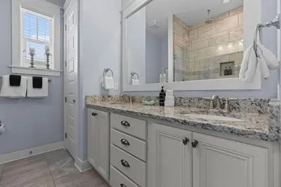 a white bathroom with a sink and a mirror at Prominence 30A - Coastal Cottage in Panama City Beach