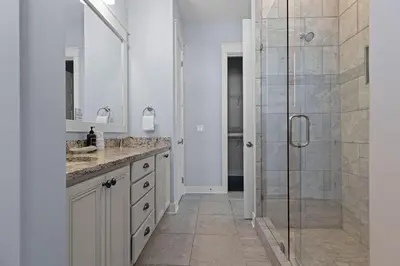a white bathroom with a shower and a sink at Prominence 30A - Coastal Cottage in Panama City Beach