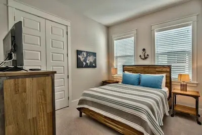 a bedroom with a bed with blue pillows and a television at Prominece 30A - Coasting Inn in Watersound Beach