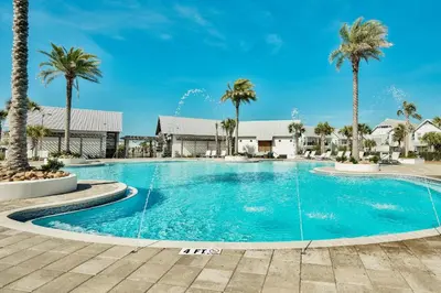 a swimming pool with palm trees in a resort at Prominece 30A - Coasting Inn in Watersound Beach
