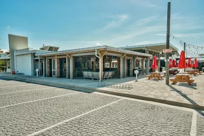 a building with tables and red umbrellas on a street at Prominece 30A - Coasting Inn in Watersound Beach