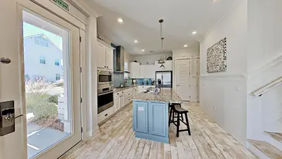 a kitchen with white cabinets and a blue island at Prominence 30A - Holiday House in Watersound Beach