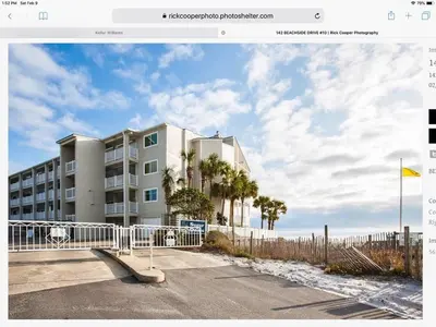 a building with a fence in front of a beach at Beach Happy - Gulf Front in Santa Rosa Beach