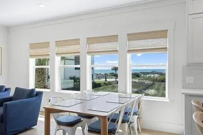 a dining room with a table and chairs and windows at 26 Blue Coast Ct in Inlet Beach