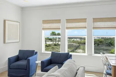 a living room with two chairs and a couch and windows at 26 Blue Coast Ct in Inlet Beach