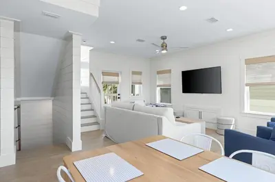 a white living room with a table and a tv at 26 Blue Coast Ct in Inlet Beach