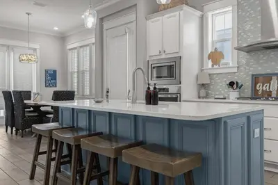 a kitchen with a blue island with stools in it at Sea Haven At Prominence in Watersound Beach