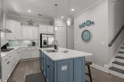 a kitchen with white cabinets and a blue island at Sea Haven At Prominence in Watersound Beach