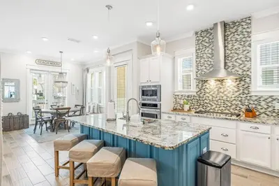 a kitchen with white cabinets and a blue island at Prominence 30A - TipSea Kitty in Santa Rosa Beach