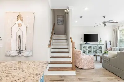 a living room with stairs and a painting on the wall at Prominence 30A - TipSea Kitty in Santa Rosa Beach